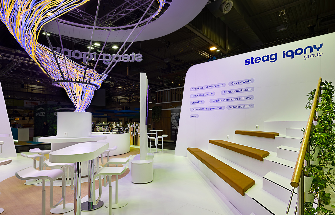 Messestand für STEAG Iqony Group mit skulpturaler Lichtinstallation und offener Kommunikationsarchitektur. Organische Formen, hochwertige Materialien und großzügige Begegnungsflächen schaffen einen modernen Markenauftritt, der Innovation, Energie und Nachhaltigkeit eindrucksvoll miteinander verbindet.