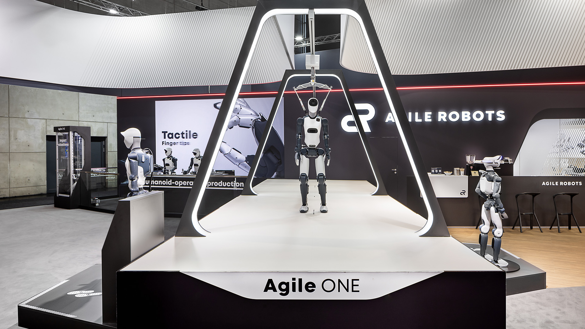 Agile ONE Live-Demonstration auf dem Messestand von Agile Robots auf der Hannover Messe: Zentraler Laufsteg mit beleuchtetem Portal präsentiert den humanoiden Roboter in einer modernen Hightech-Umgebung und macht Robotik sowie industrielle Automatisierung eindrucksvoll erlebbar.modern, high-tech setting, offering an impressive hands-on experience of robotics and industrial automation.