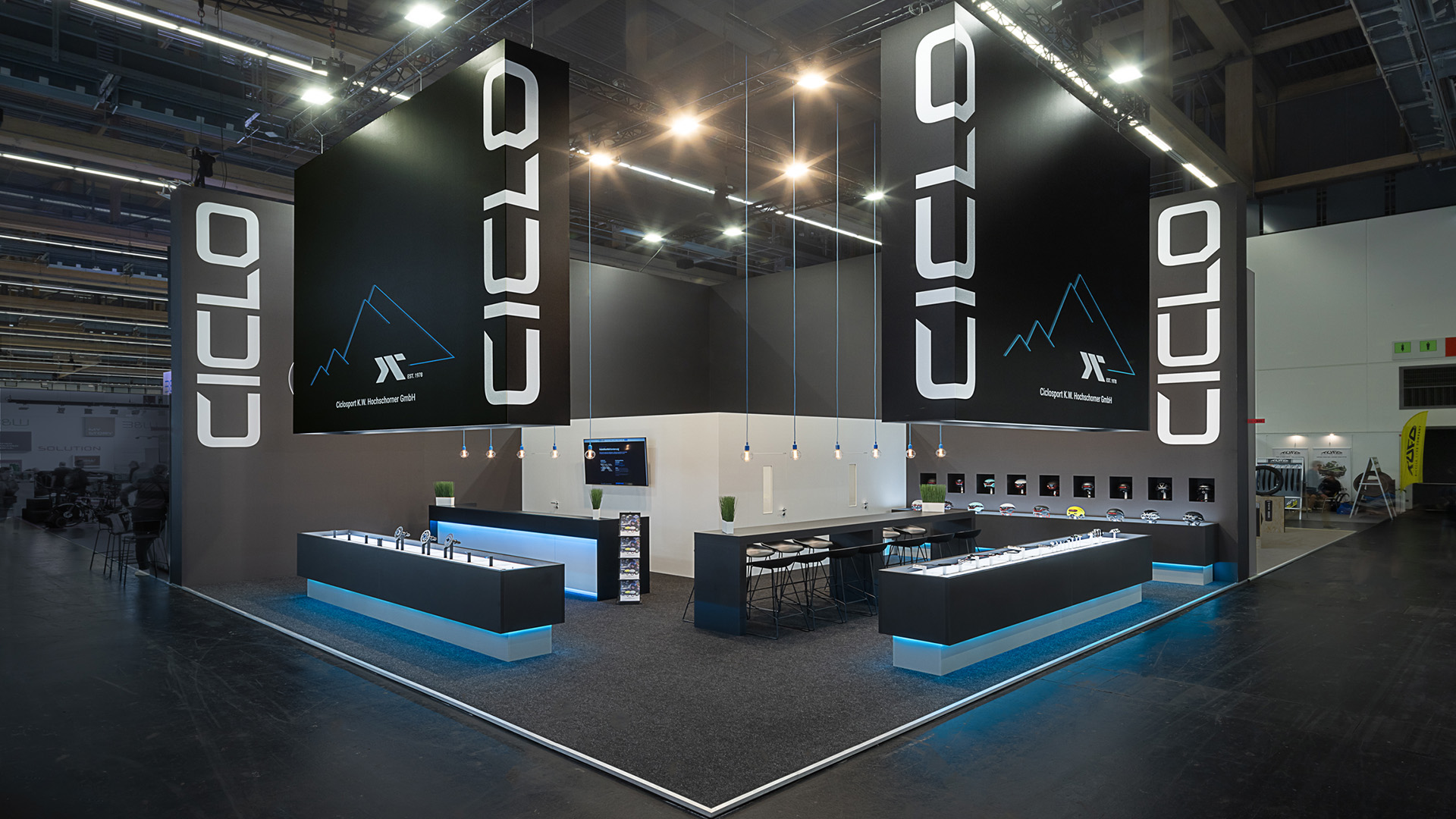 Moderner Messestand für Ciclo Sport auf der Eurobike in Frankfurt mit großformatigen Logoelementen, hinterleuchteten Produktpräsentern und kontrastreichem schwarz-weißem Standdesign für e-Bike-Komponenten.