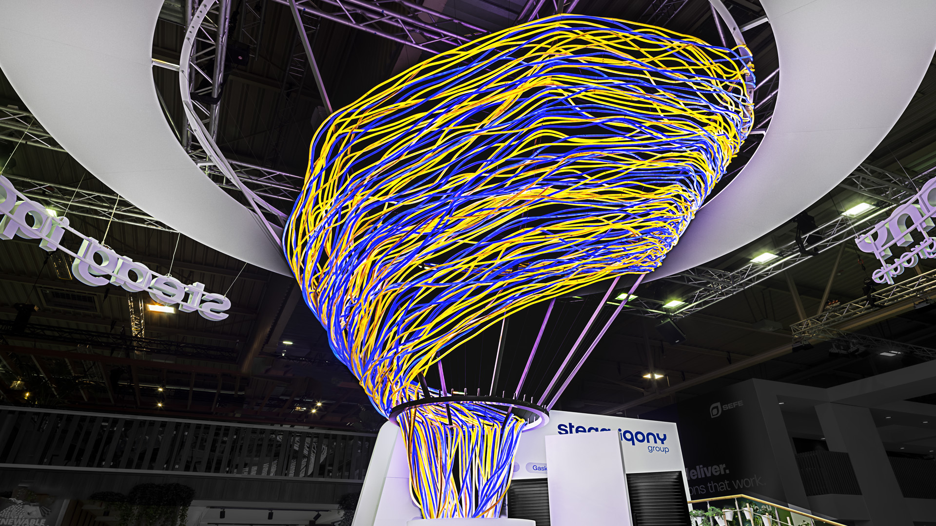 Detailaufnahme der skulpturalen Lichtinstallation des Messestands der STEAG Iqony Group auf der E-world. Die dynamisch verflochtenen Lichtlinien symbolisieren Energie, Vernetzung und Transformation und bilden das prägende Gestaltungselement des gesamten Markenauftritts – Design von Zillich für Objekt Consult.