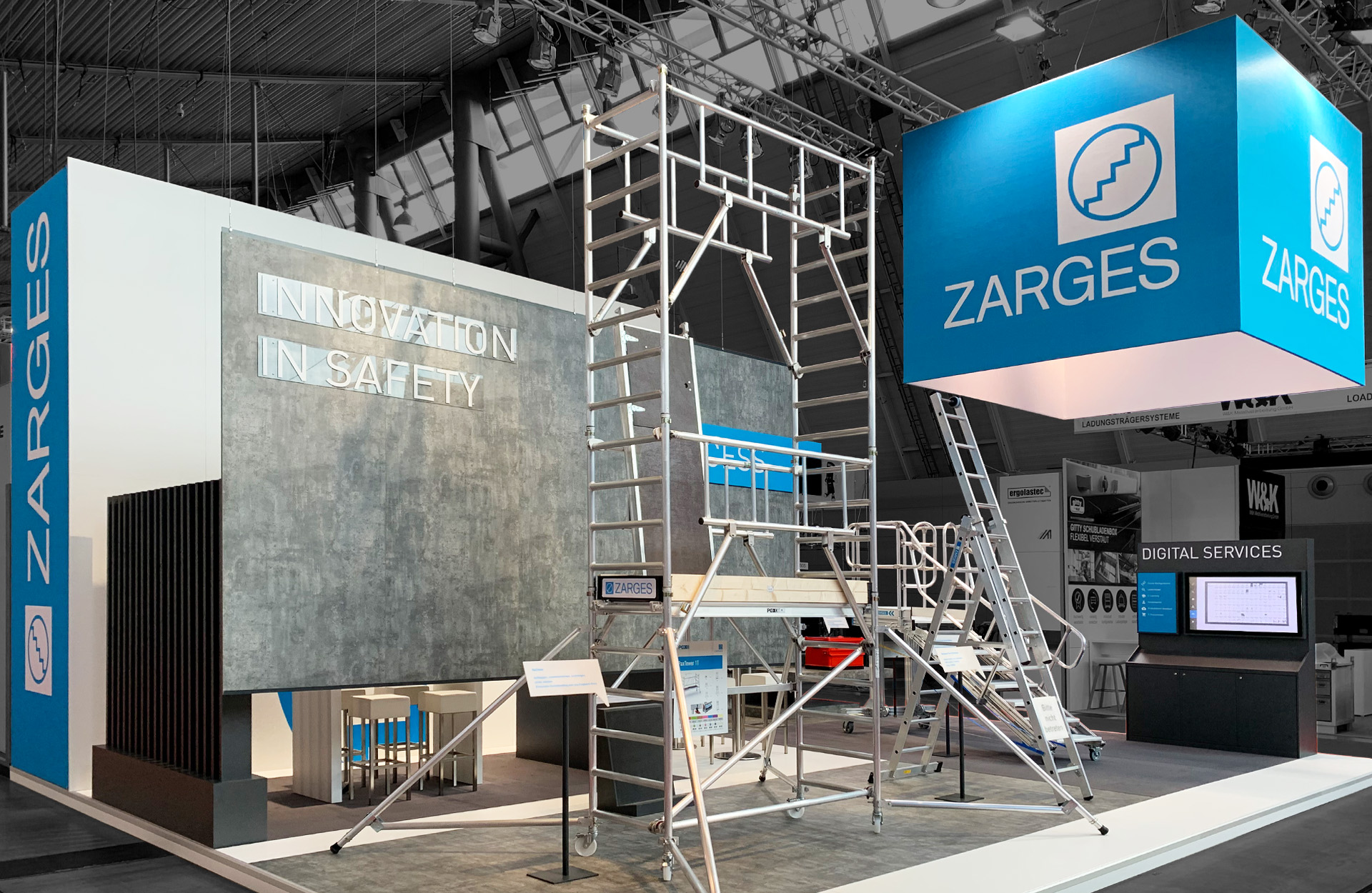 Messestand von ZARGES auf der LogiMAT in Stuttgart mit großformatigem, hinterleuchtetem Logokubus und eindrucksvoller Präsentation von Aluminium-Gerüsten, Leitern und Zugangslösungen. Die offene Standarchitektur kombiniert markante Markenpräsenz, Live-Demonstrationen und moderne Beratungsbereiche für einen aufmerksamkeitsstarken Messeauftritt.
