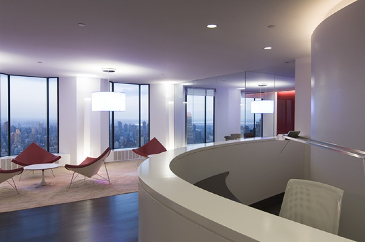 Moderne Empfangs- und Loungezone einer hochwertigen Büroetage in New York mit geschwungener Rezeption, Designmöbeln, bodentiefen Fenstern und Blick auf die Skyline von Manhattan.
