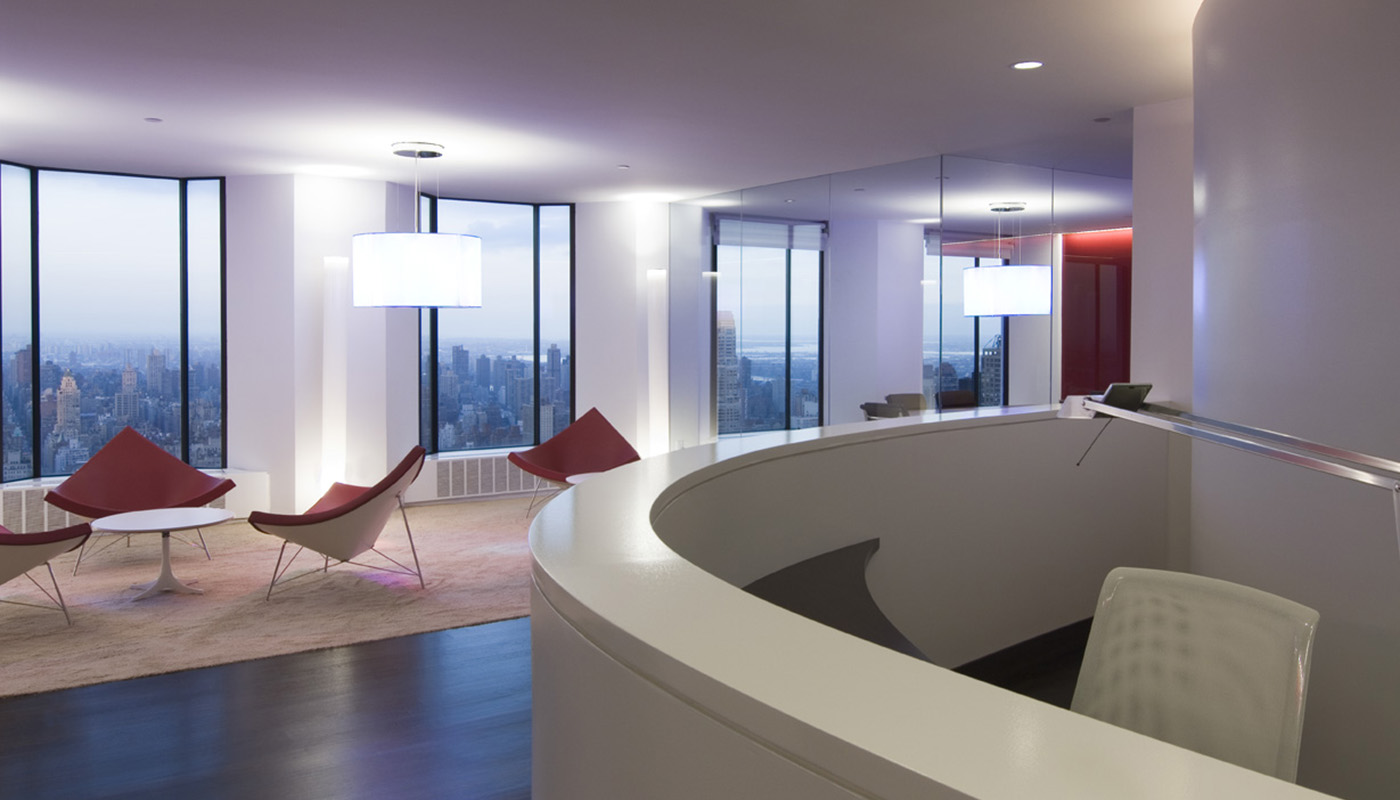 Moderne Empfangs- und Loungezone einer hochwertigen Büroetage in New York mit geschwungener Rezeption, Designmöbeln, bodentiefen Fenstern und Blick auf die Skyline von Manhattan.
