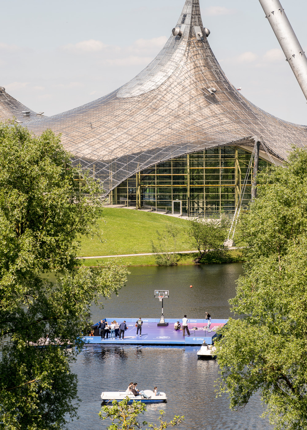 A floating basketball court for FC Bayern Basketball and BMW in Munich's Olympic Park, set against the striking architecture of the Olympic Stadium.