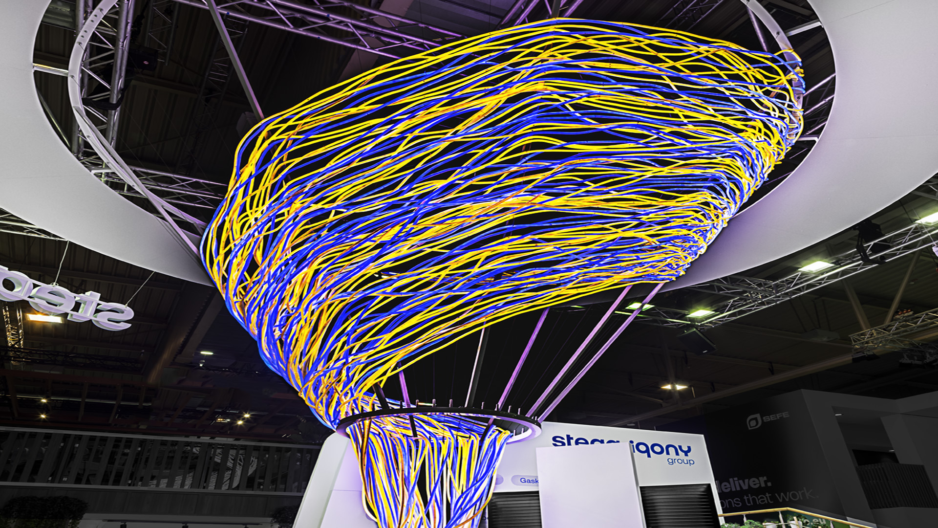 Detailaufnahme der spektakulären Lichtinstallation auf dem Messestand der STEAG Iqony Group auf der E-world. Die organisch geformte, schwebende Skulptur visualisiert Energieflüsse, Vernetzung und Transformation und bildet das prägende architektonische Highlight des gesamten Messeauftritts.