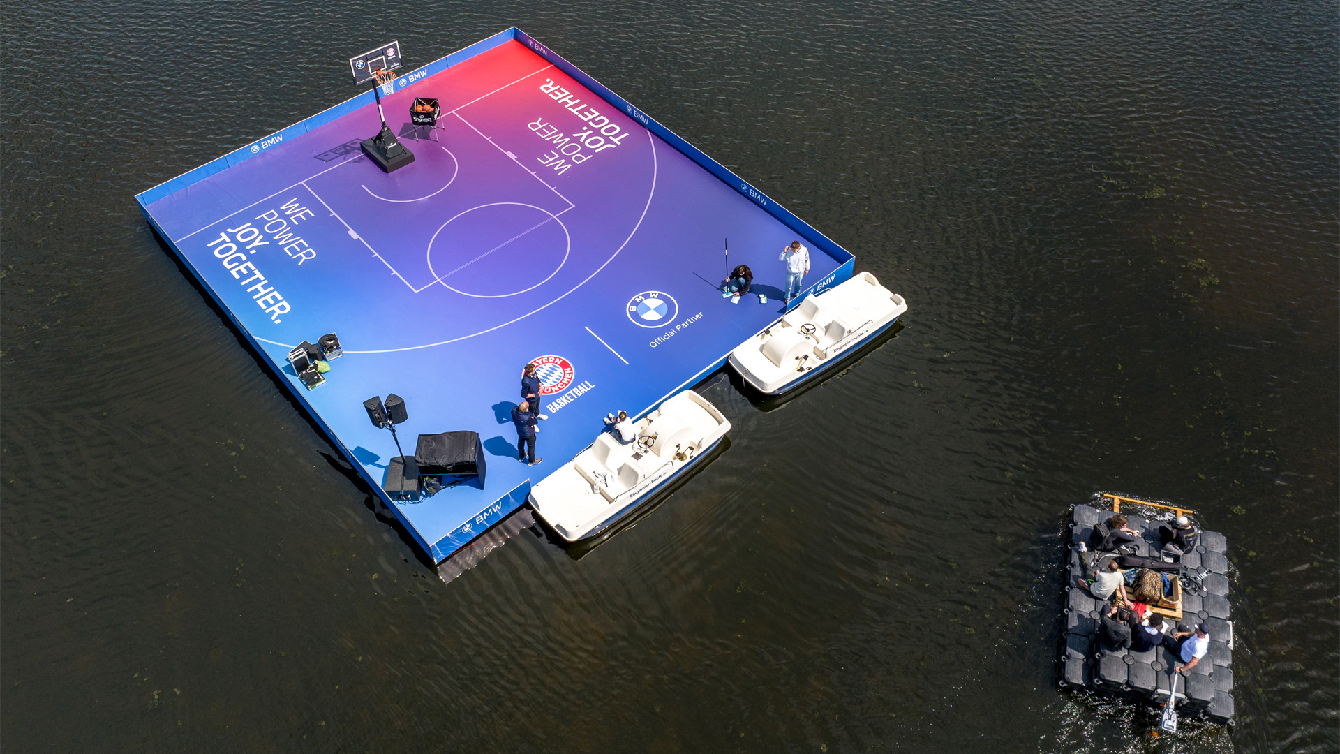 Close-up of the floating basketball court in Munich’s Olympic Park—innovative event architecture and a temporary event space by PLANAG Design. Aerial view from above showing the floating dinghy