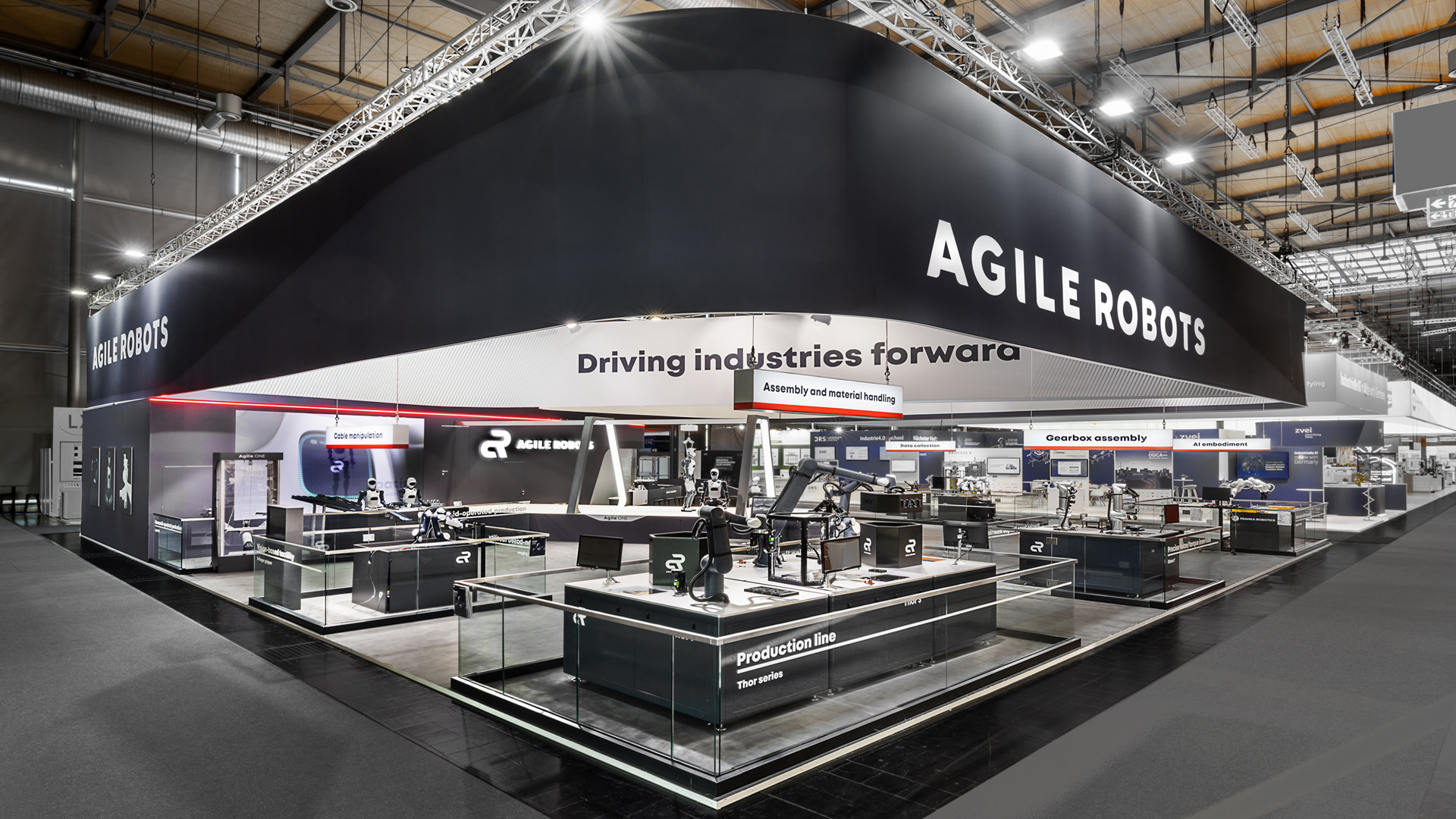 Großzügiger Messestand von Agile Robots auf der Hannover Messe mit markantem, umlaufendem Deckenbanner, offenen Demonstrationsflächen und Live-Anwendungen für industrielle Robotik. Die moderne Standarchitektur mit klaren Sichtachsen, Glasabgrenzungen und hochwertiger Lichtinszenierung präsentiert innovative Automatisierungs- und KI-Lösungen in einem internationalen Messeumfeld.