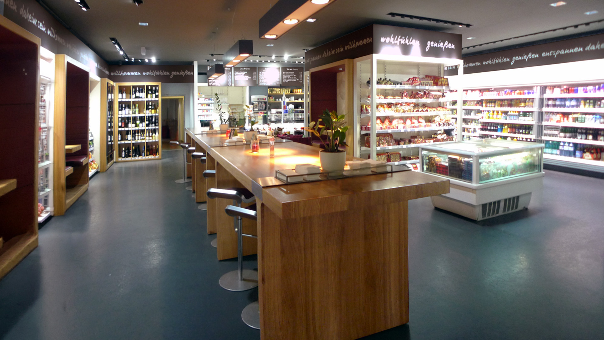 Gesamtansicht des Kramer's Store-Konzepts in Salzburg und Innsbruck mit Café, Bar, Convenience Store und zentralem Gemeinschaftstisch.