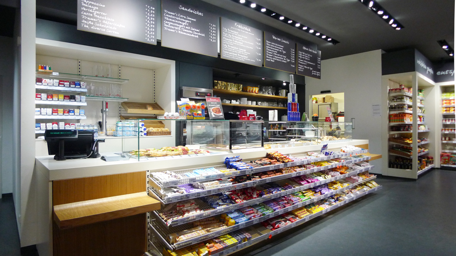 Innenraum von Kramer's in Salzburg und Innsbruck mit Café, Bar und Convenience Store, hochwertiger Verkaufstheke sowie integriertem Nahversorgungskonzept.