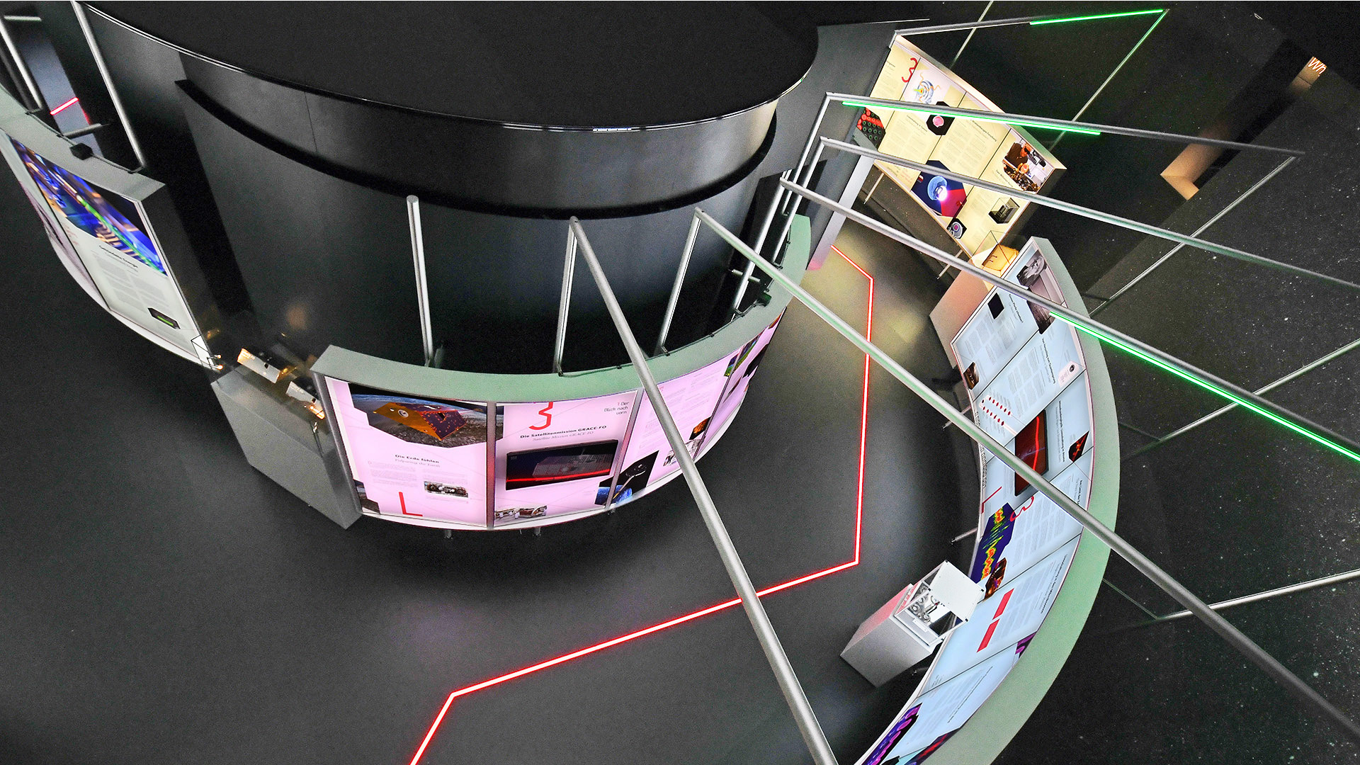 Detailansicht der Ausstellung „Laser Licht Leben“ im ESO Planetarium Garching mit radial angeordneten Leuchtkästen, interaktiven Exponaten, zentralem Ausstellungsraum und LED-Lichtinszenierung zur Vermittlung moderner Lasertechnologie.