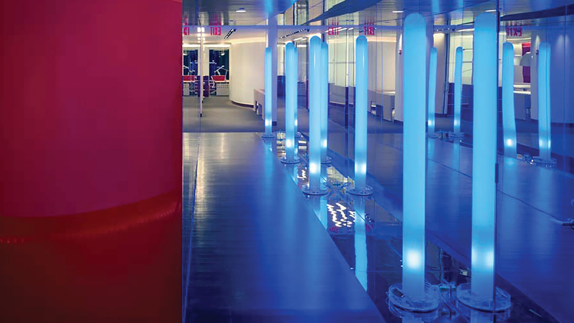 Moderner Büroflur mit beleuchteten Lichtstelen, Glaswänden und hochwertiger Innenarchitektur in einer exklusiven Büroetage in New York.