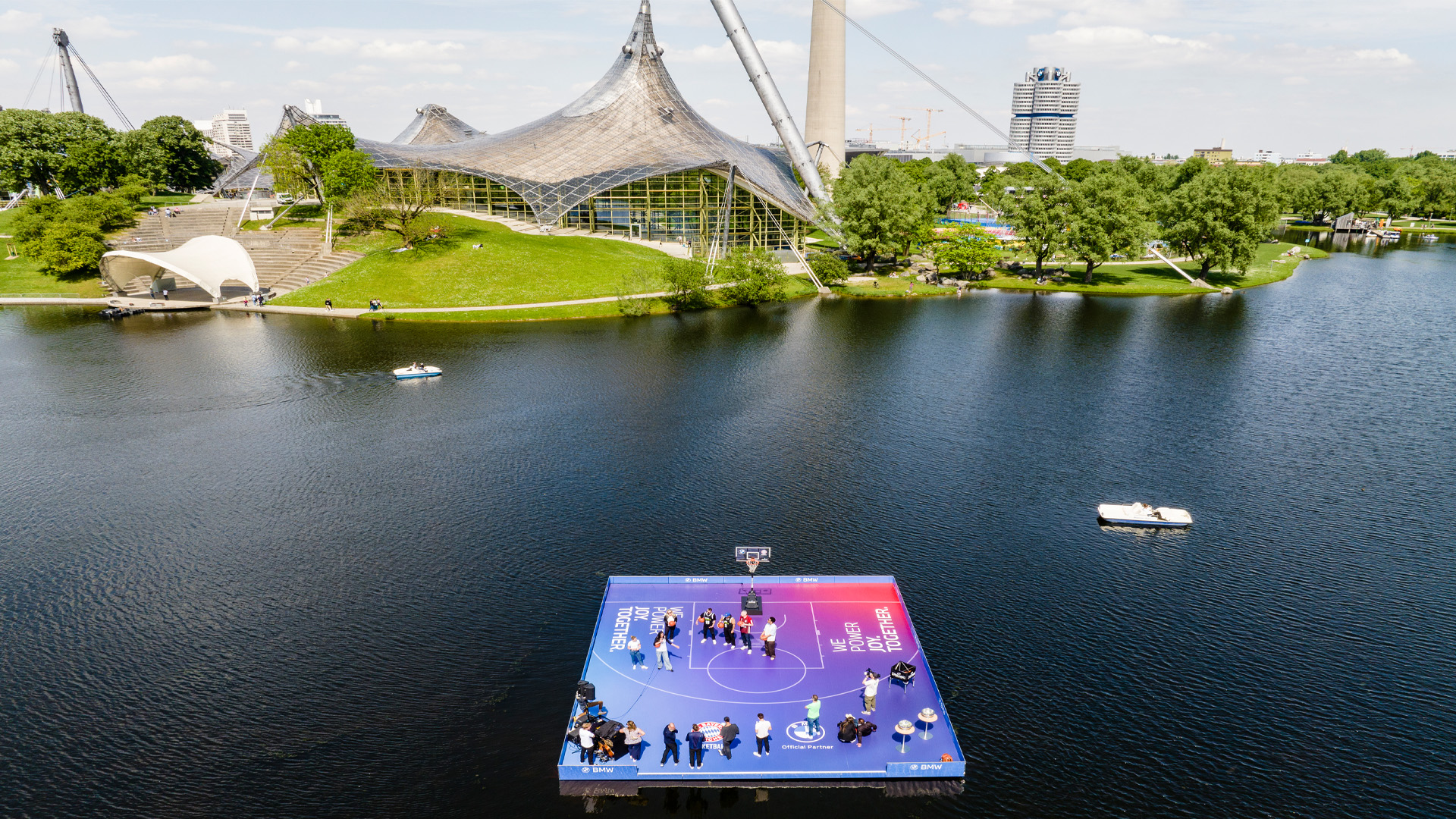 Floating basketball court in Munich’s Olympic Park, in front of the Olympic Tower and the Olympic Stadium—innovative event architecture and a temporary event space by PLANAG Design. Aerial view from above