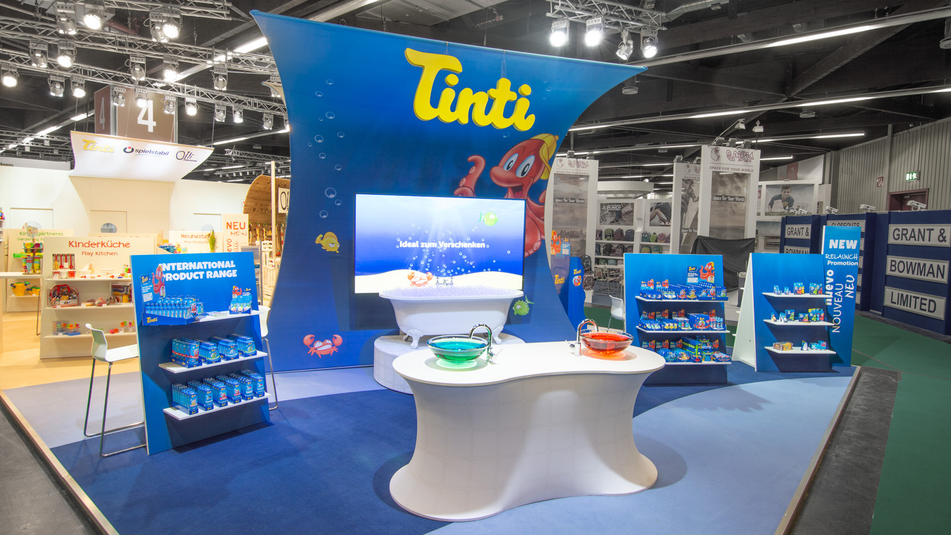 Tinti’s booth at the Nuremberg Toy Fair. The striking, curved textile architecture creates a distinctive visual impact from a distance and serves as the centerpiece of an interactive brand experience. Interactive stations, product displays, and digital media combine play, water, and color to create an emotional brand world for children and families.